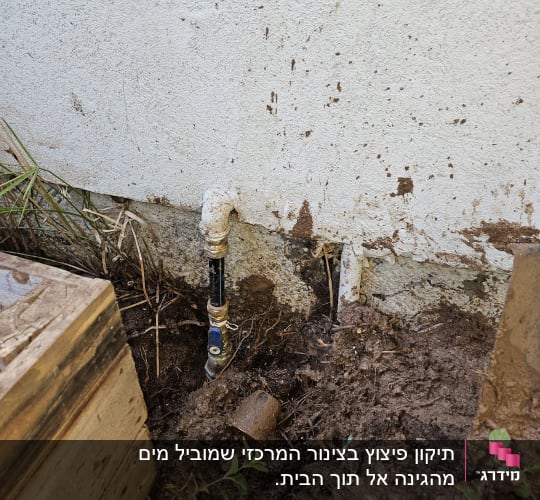 צינור מים מחובר לקיר עם אדמה מסביב